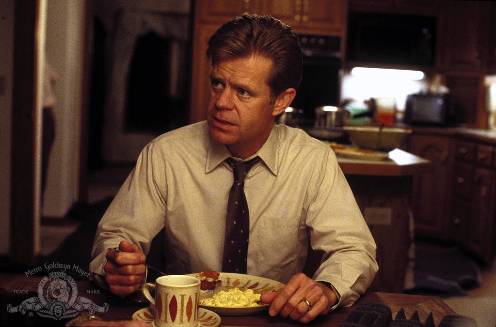 William H. Macy as Jerry Lundegaard sitting at the kitchen table with a nervous expression, reflecting the desperation of his failed criminal plot to solve his financial troubles.