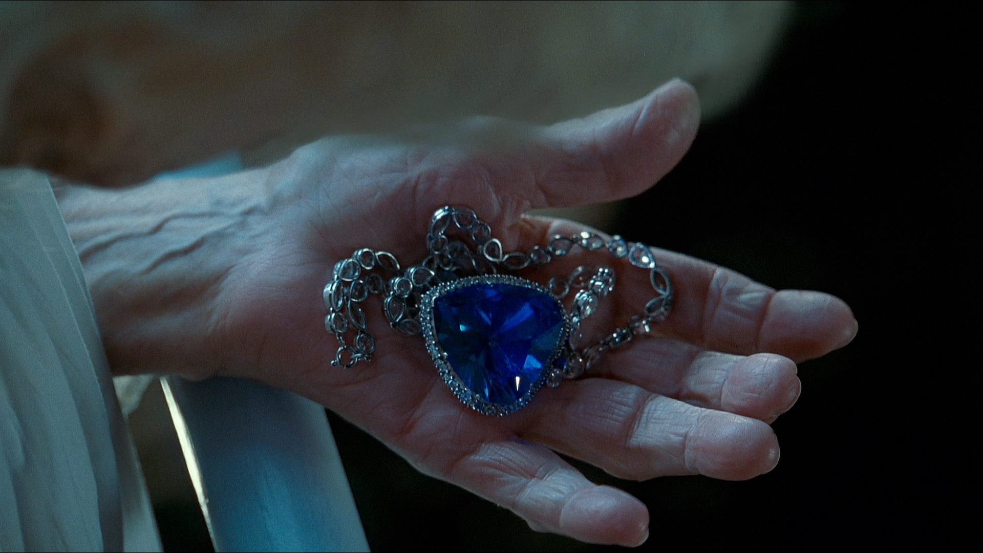 Close-up of an elderly Rose holding the Heart of the Ocean necklace. The iconic blue diamond plays a symbolic role in the film’s love story and historical narrative.